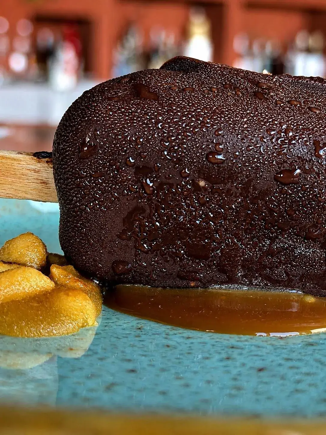 Piatto di carne glassata con salsa, su piatto turchese